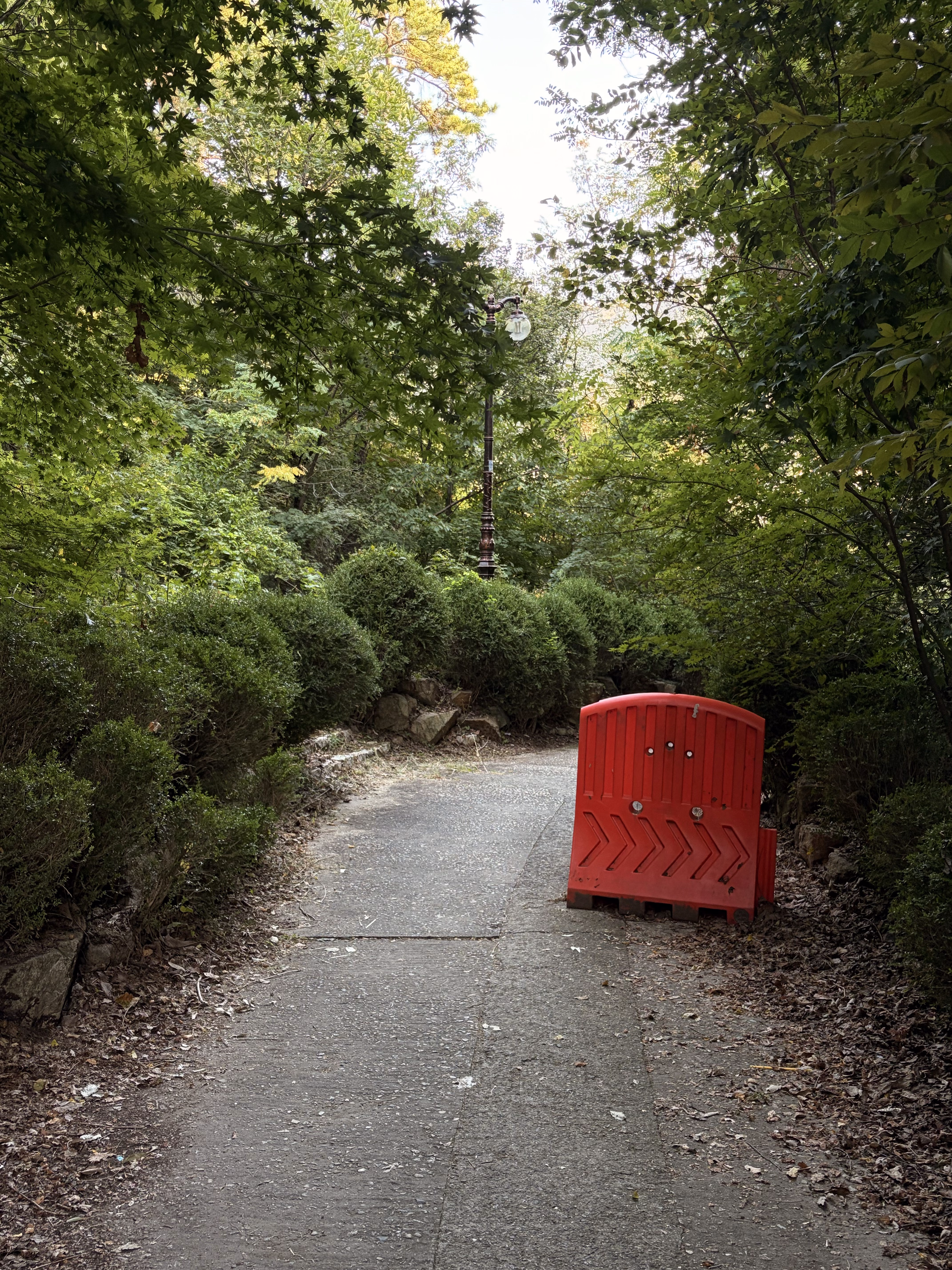 A red barrier on a path surrounded by trees.